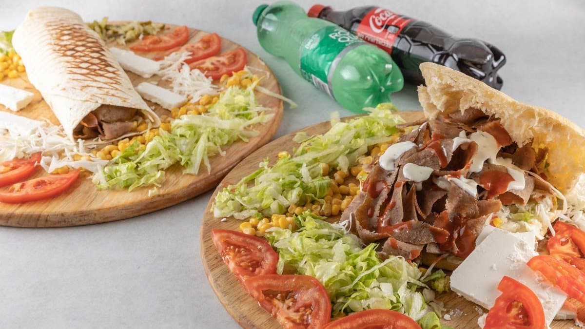 Kebab u tortilji zamotan i poslužen na drvenoj dasci s prilozima