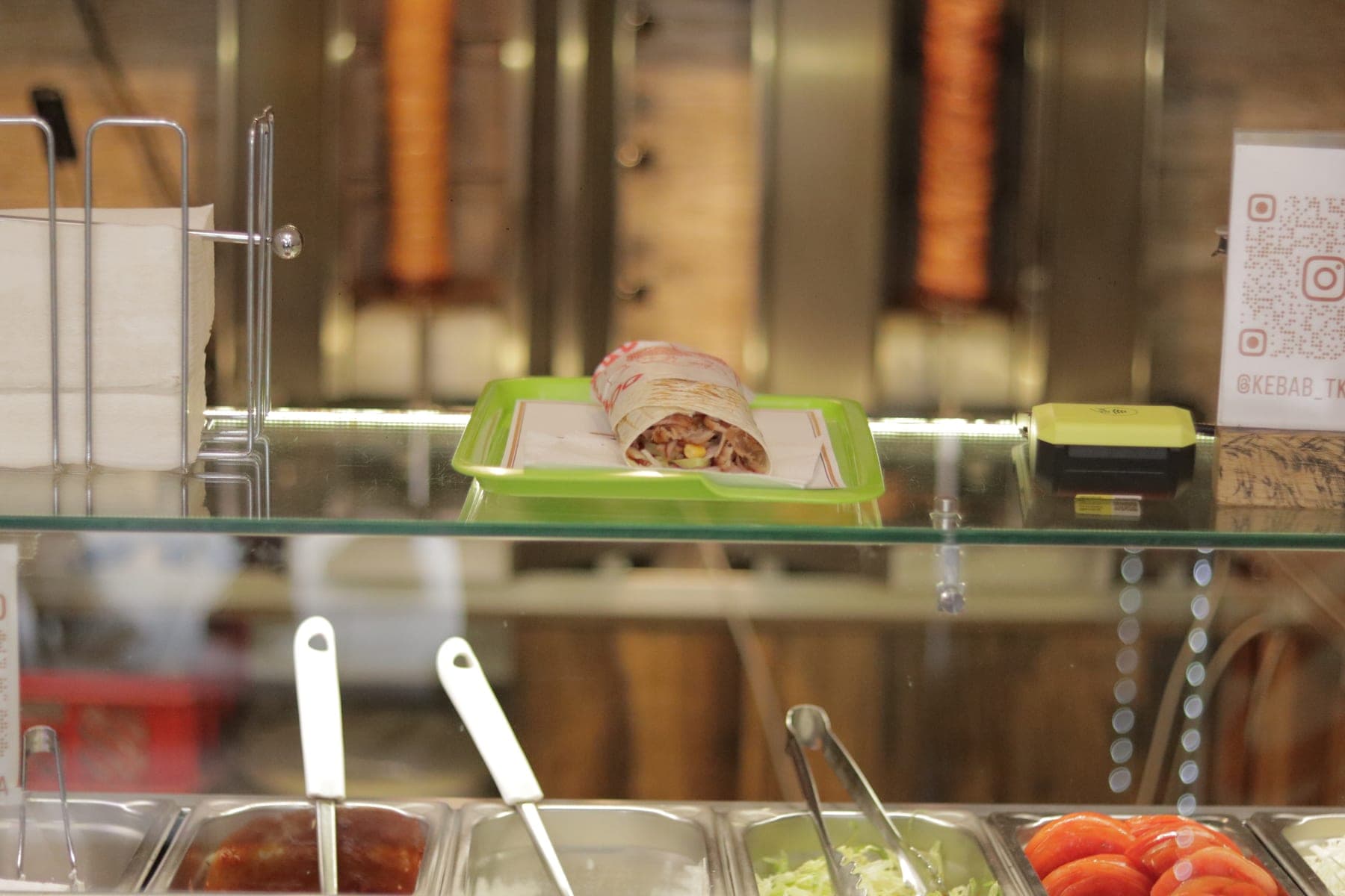 Pult Kebab Tkalča s prilozima i umacima, iza njega dva ražnja s mesom